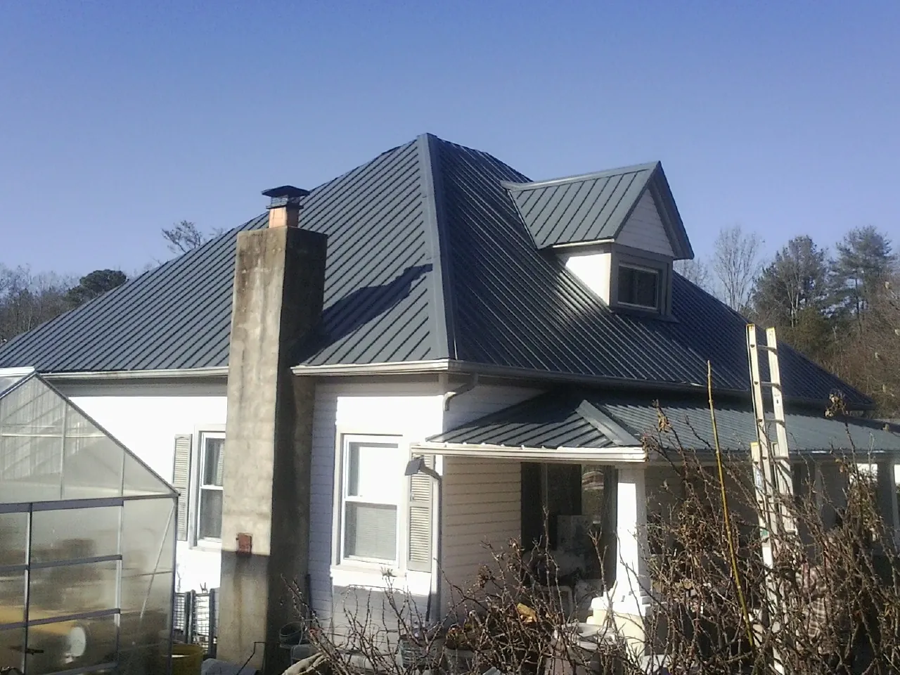 Dark blue standing seam metal roof on a white farmhouse with dormer — Slate & Tile Roof Repair by Roofing Brothers in Remlap