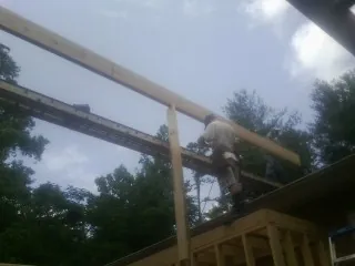 Carpenter setting a ridge beam over a new addition frame — Ice Dam Removal by Roofing Brothers in Remlap