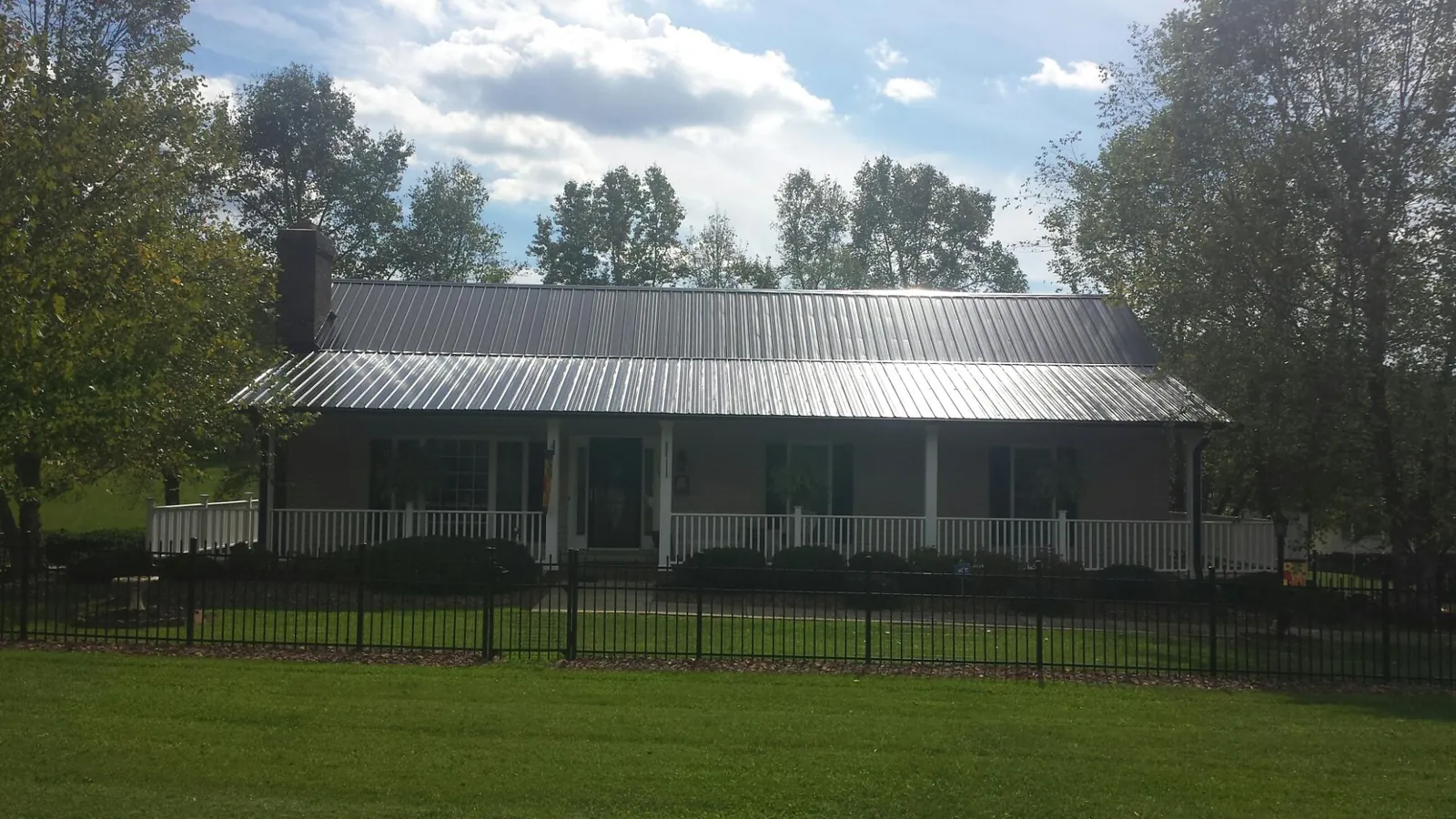 Gray metal roof on a brick ranch with a full width front porch — Gutter Guard Installation work by our crew in Remlap