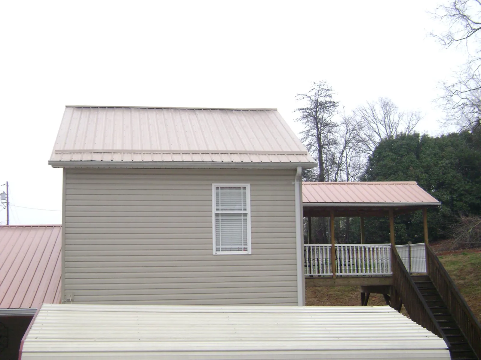 Tan metal roofs on a two story addition and attached porch, from a Roof Replacement job in Remlap