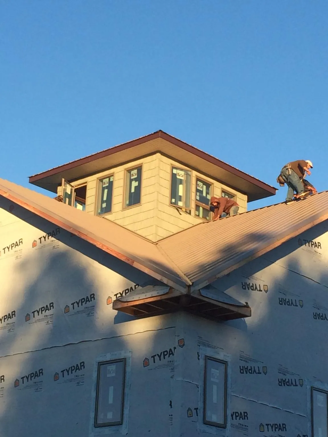Roofers working around a rooftop cupola on a new metal roof at sunset — Roof Waterproofing in Remlap by Roofing Brothers